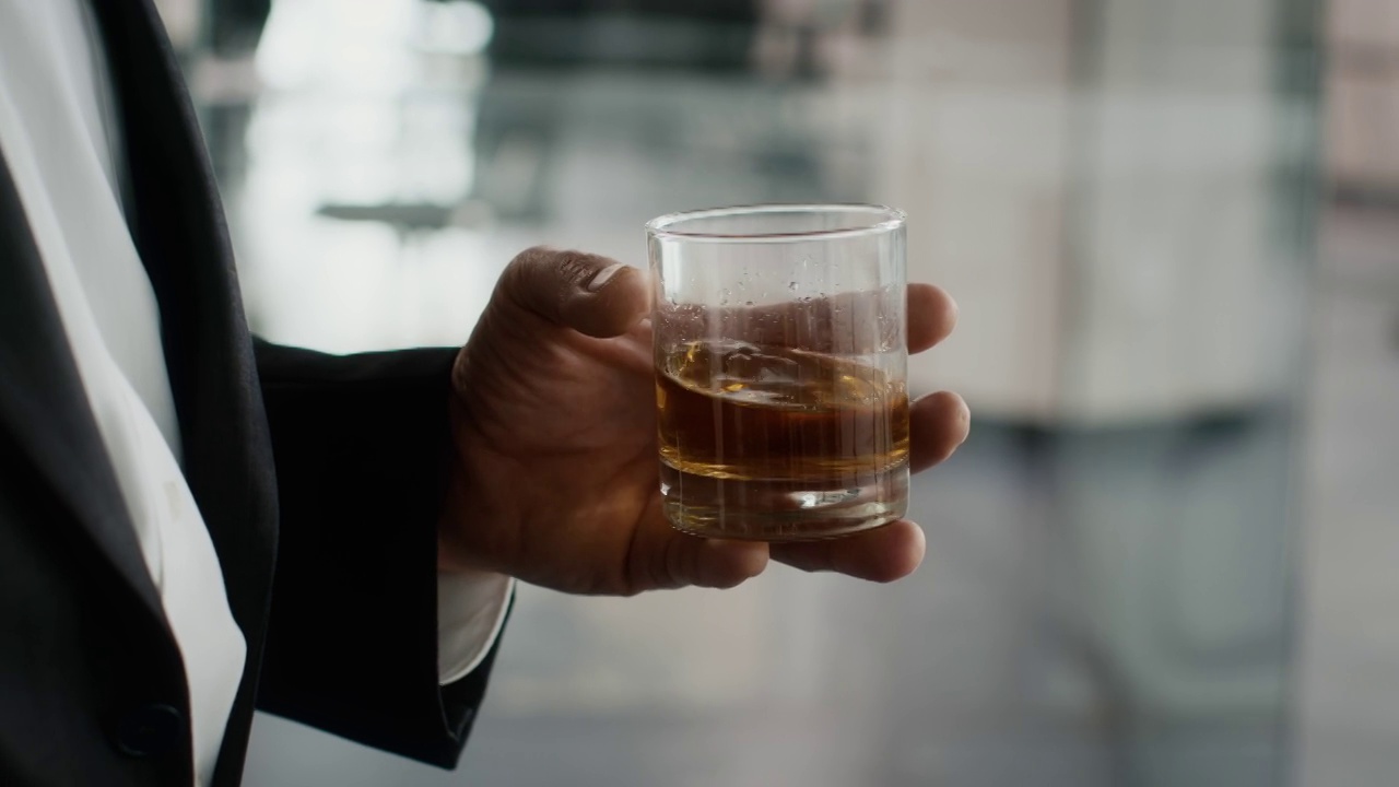 裁剪镜头的商人拿着玻璃与威士忌在办公室视频素材