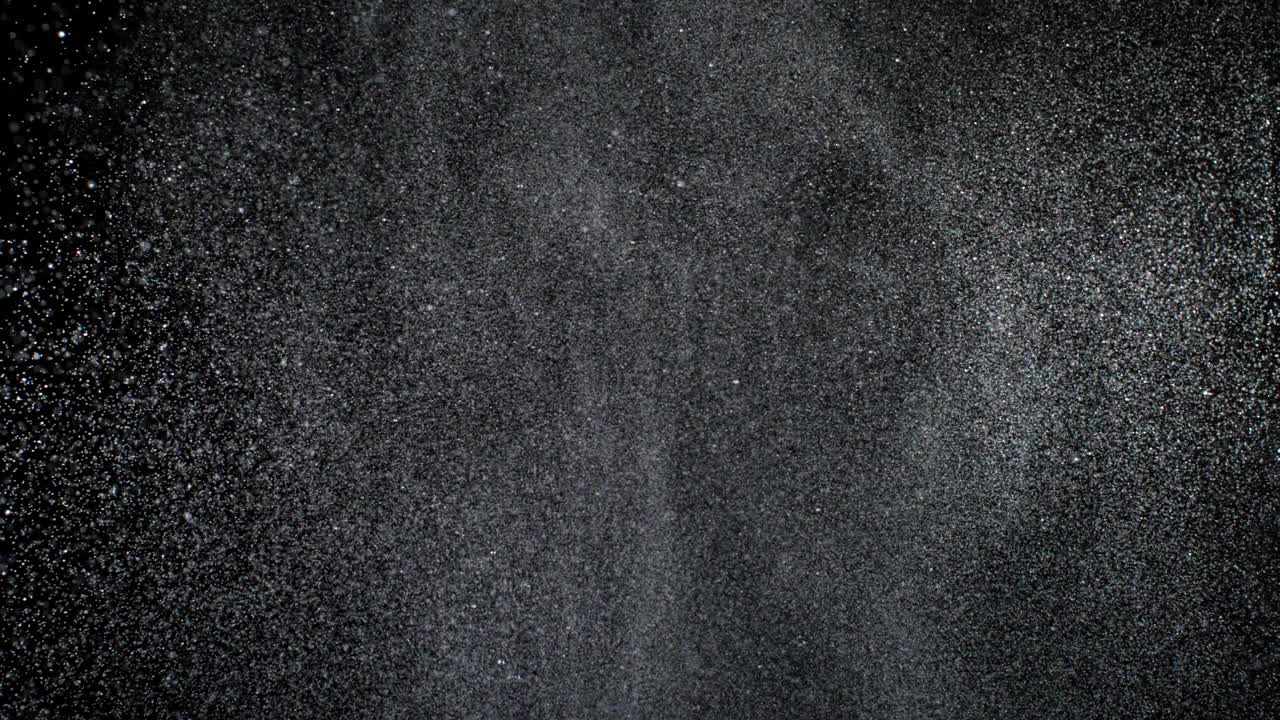 特写和超级慢动作从底部喷洒水，在黑色背景上用星云粒子填充整个画面视频下载