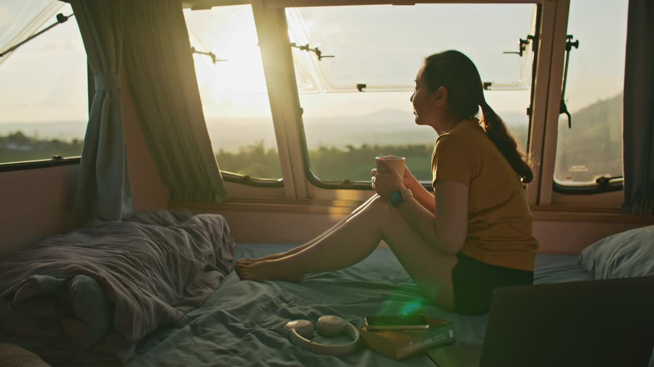 度假期间，女性在货车里放松。年轻女子乘坐露营车欣赏山景视频素材