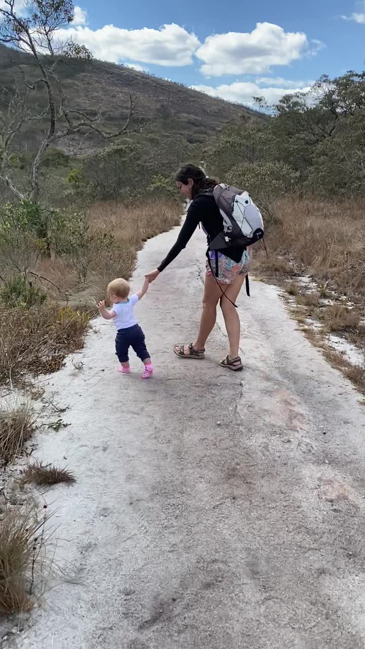 母亲牵着蹒跚学步的小女孩在徒步旅行中行走和跌倒视频下载
