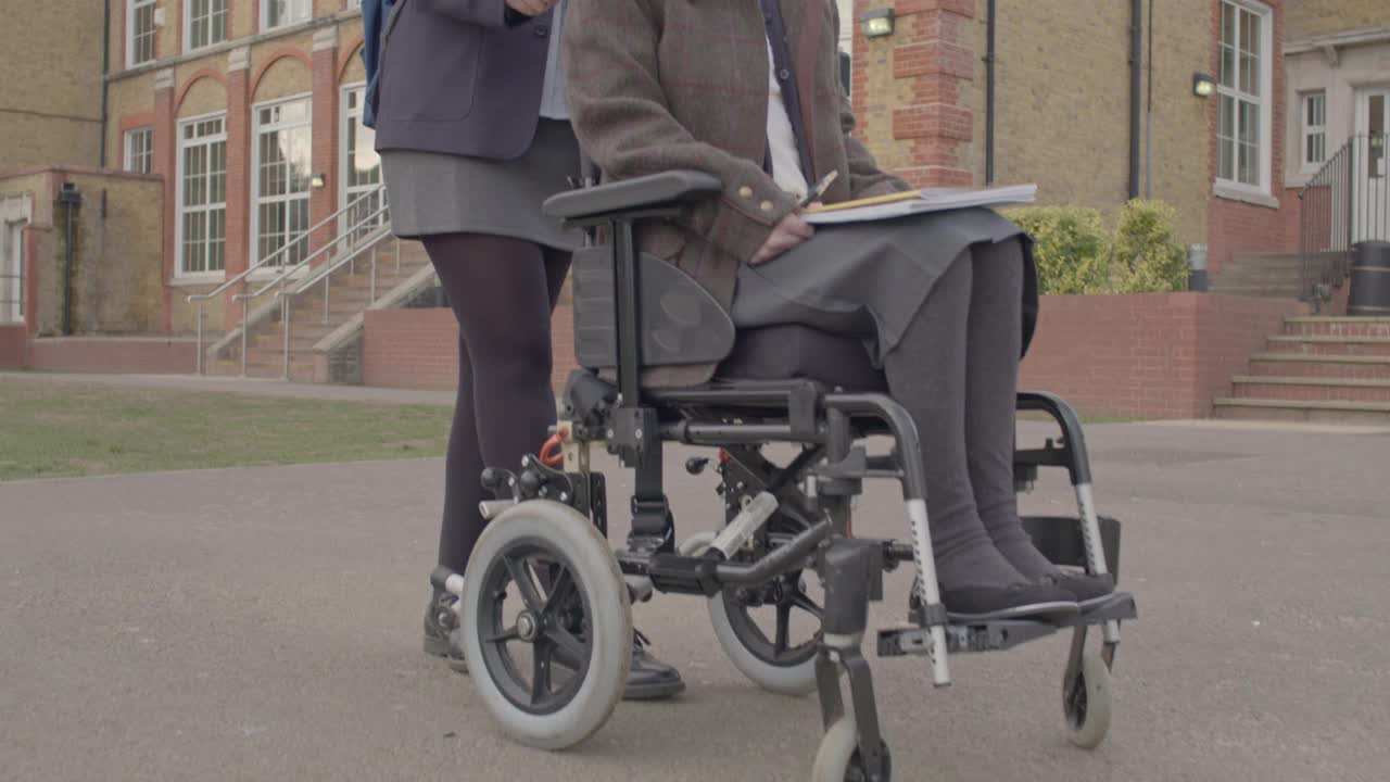 英国少年在校园里推着轮椅上的同学视频素材