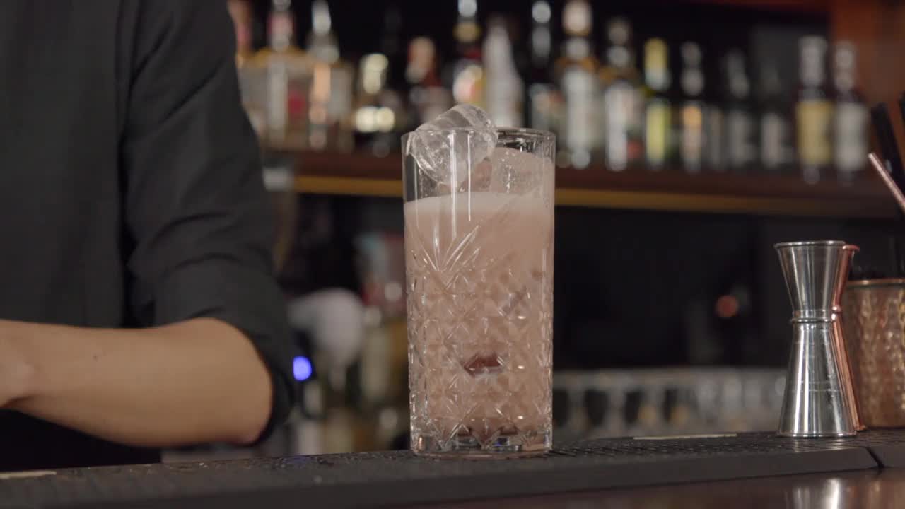 调酒师将瓶装苹果酒加到加冰的鸡尾酒中并制造泡沫视频下载