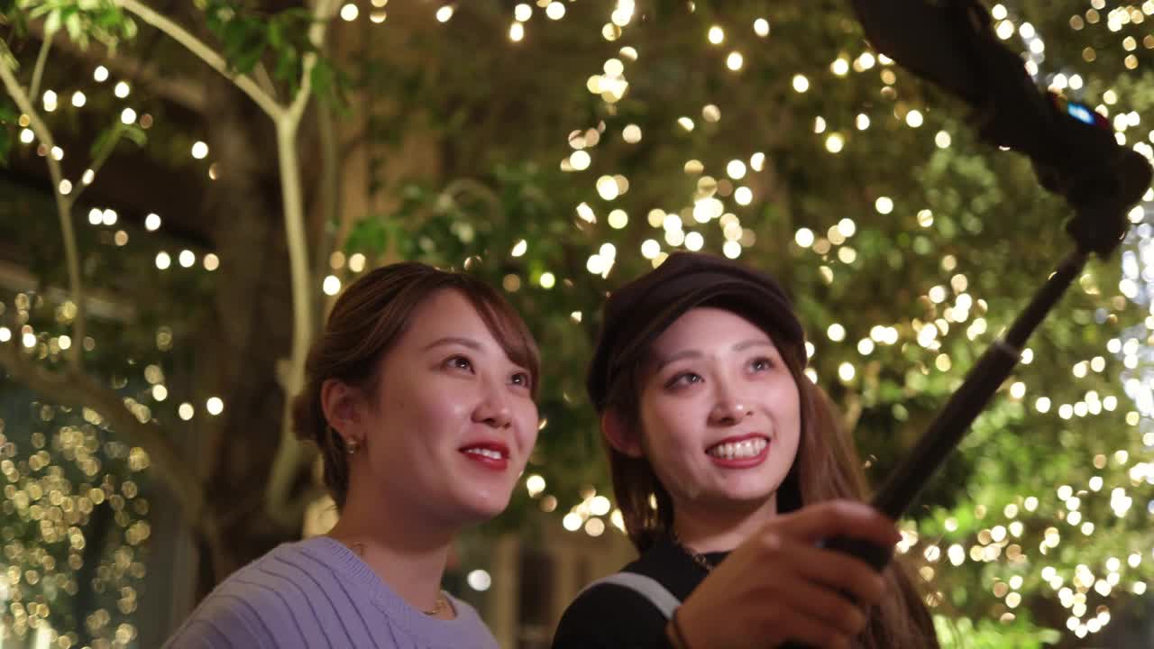 年轻的女性朋友在圣诞节的灯光下自拍视频视频下载