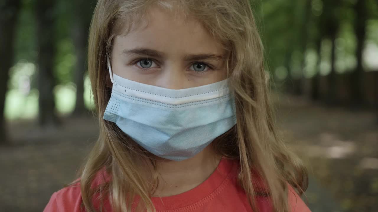 儿童戴口罩保护自己免受病毒空气污染。冠状病毒流行Covid-19。流感冠状病毒。流行，小女孩在城市街道上戴着防护面具的肖像。视频素材