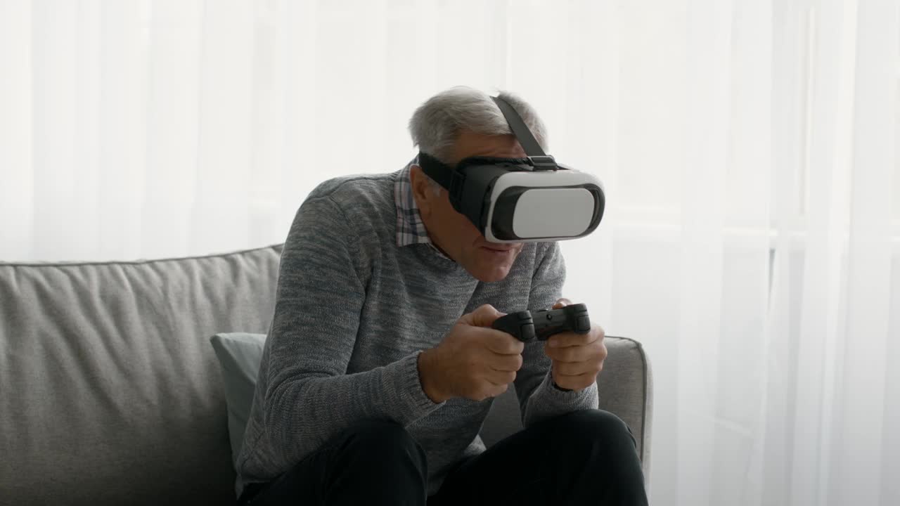 兴奋的老人戴着VR头盔在家玩视频游戏视频素材