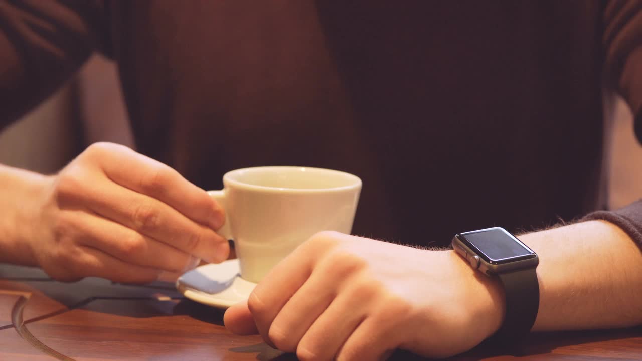 大胡子男子喝咖啡和使用手表的近景视频素材