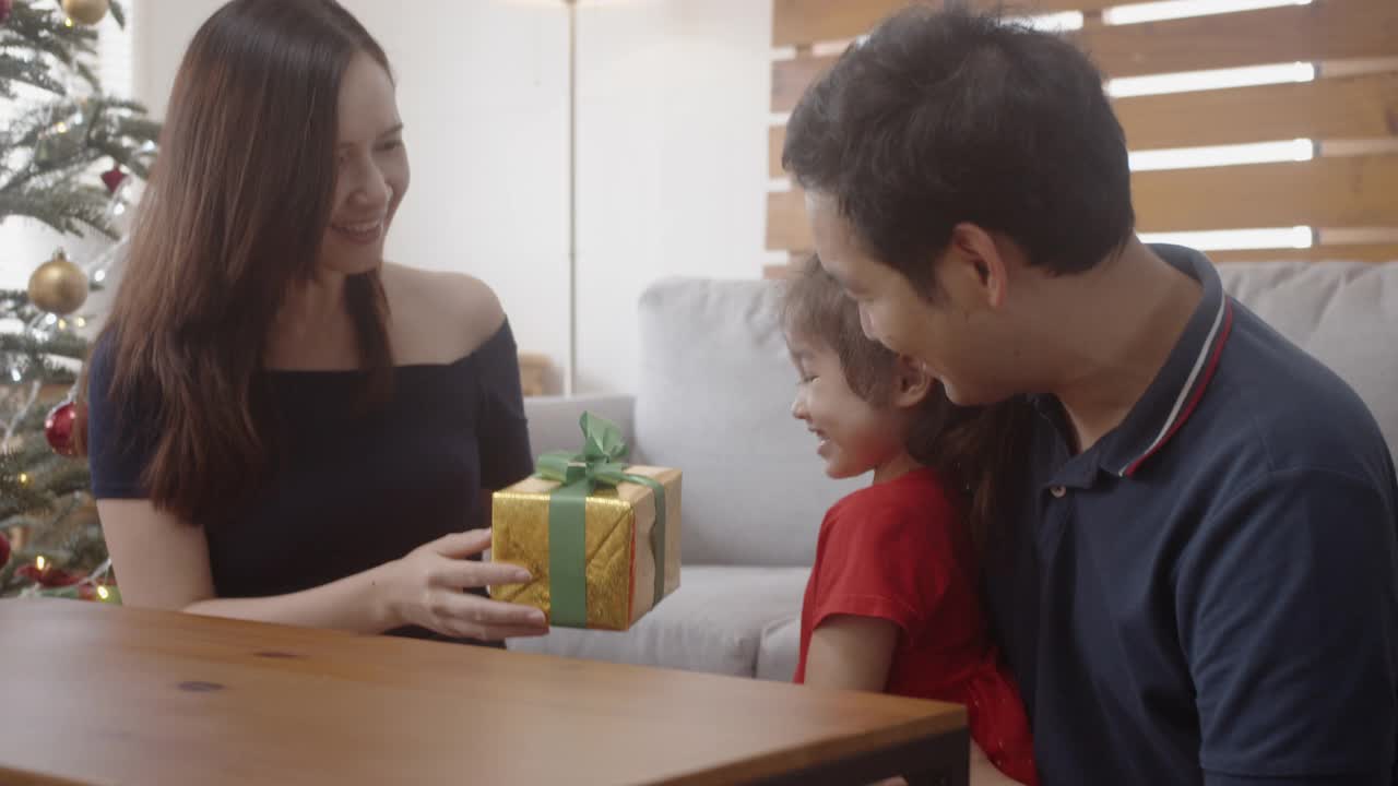 年轻的亚洲母亲给礼物盒给她的小女儿惊喜。视频素材