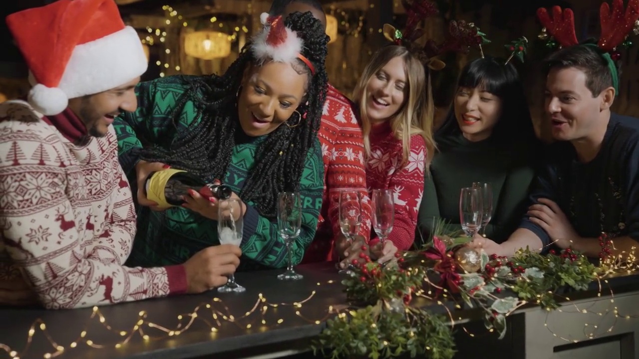 跟踪镜头接近朋友倒香槟在圣诞节庆祝活动视频下载