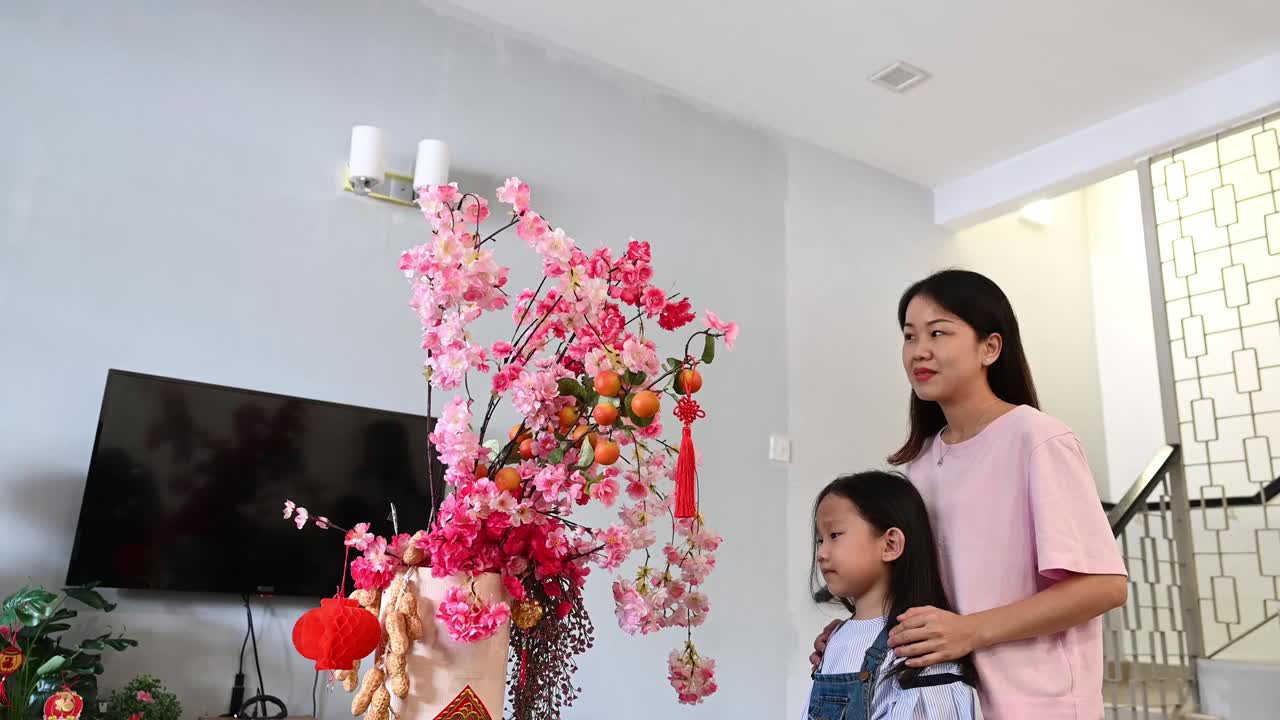 亚洲中国妇女和她的女儿装饰房子的客厅与阴户柳树和装饰准备即将到来的中国新年视频素材