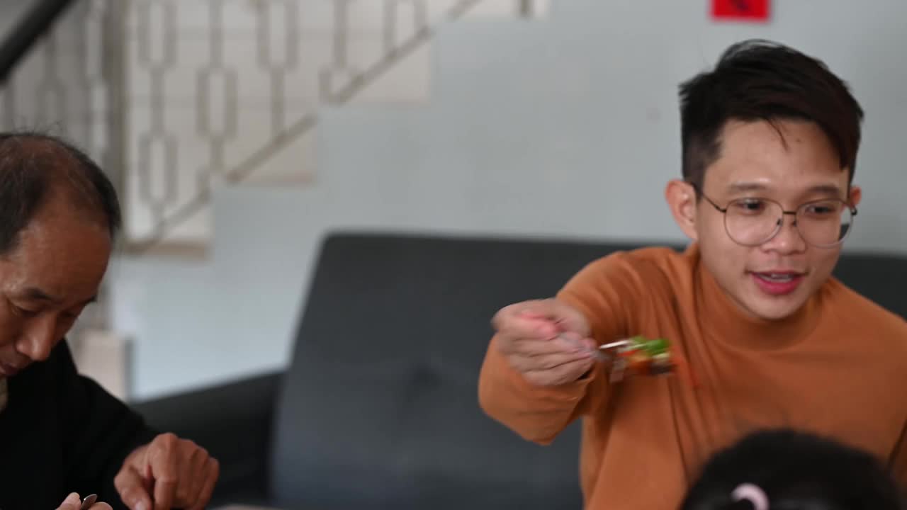 中国新年期间，一名亚洲男子在家享受团圆饭，并与母亲分享食物视频素材