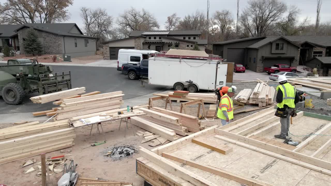 平移多莉拍摄三个人框架人员移动周围的材料和钉在一起的木框架墙被提高在一个新的住宅建筑工地视频素材