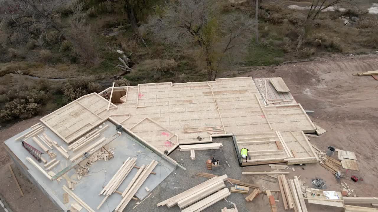降低倾斜无人机拍摄的Framer Carpenter建筑木框架墙在一个新房子建设视频下载