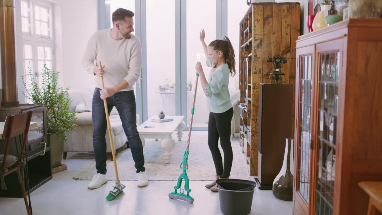 一个爸爸和女儿在家里打扫客厅时玩的4k视频视频素材