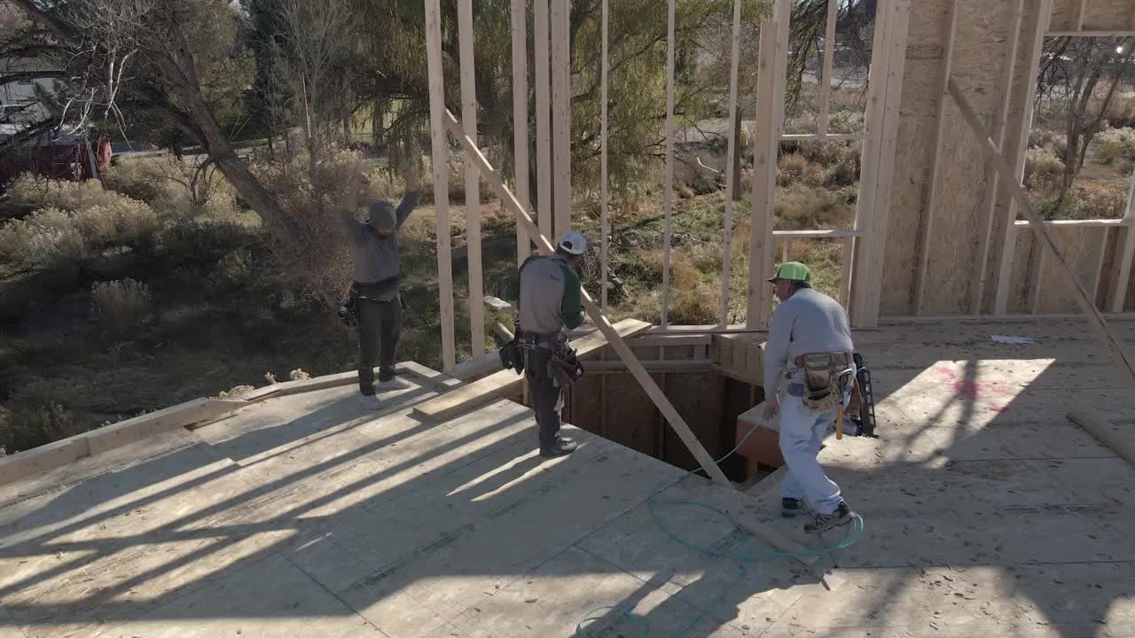 框架工作人员正在完成他们刚刚在住宅建筑工地搭建的一面墙视频素材