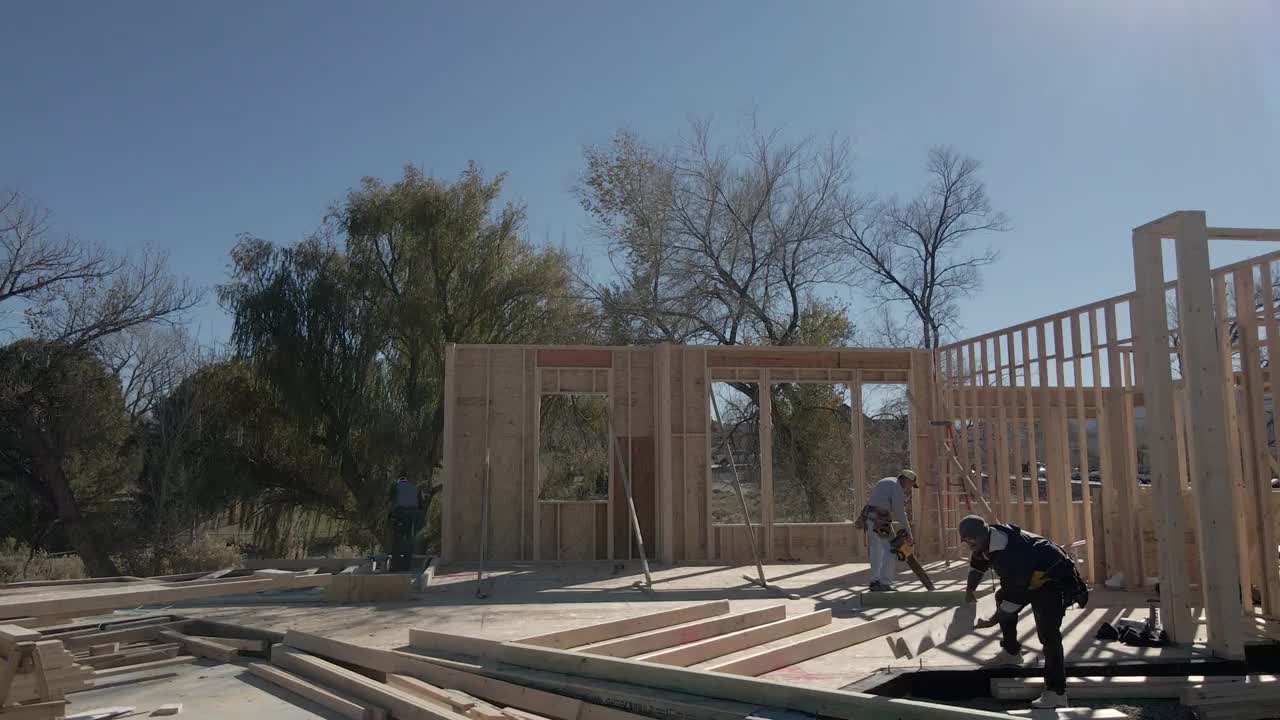 无人机住宅建筑工地与三个高加索框架木匠工作的墙壁视频素材