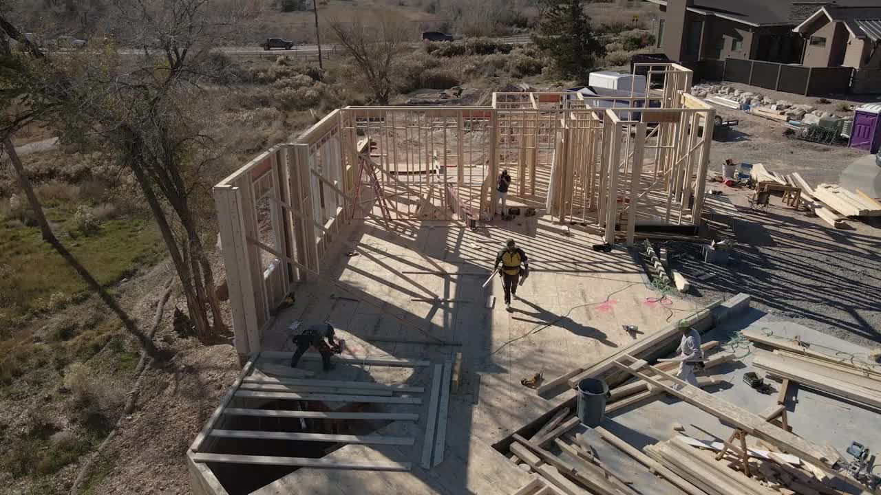 无人机住宅建筑工地与三个高加索框架木匠工作的墙壁视频下载