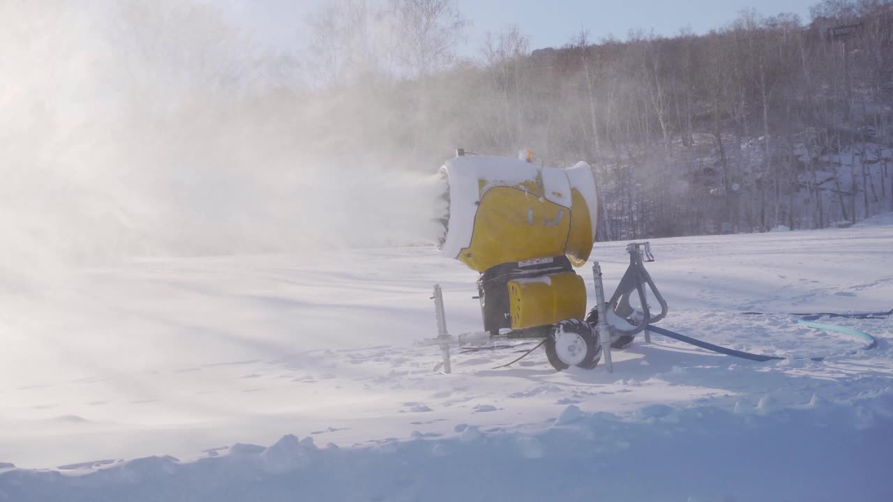 冬季星期天，滑雪场的雪炮。造雪机在森林、蓝天制造人工雪。涡轮在冷空气中喷水。山地运动中滑雪道的准备视频下载