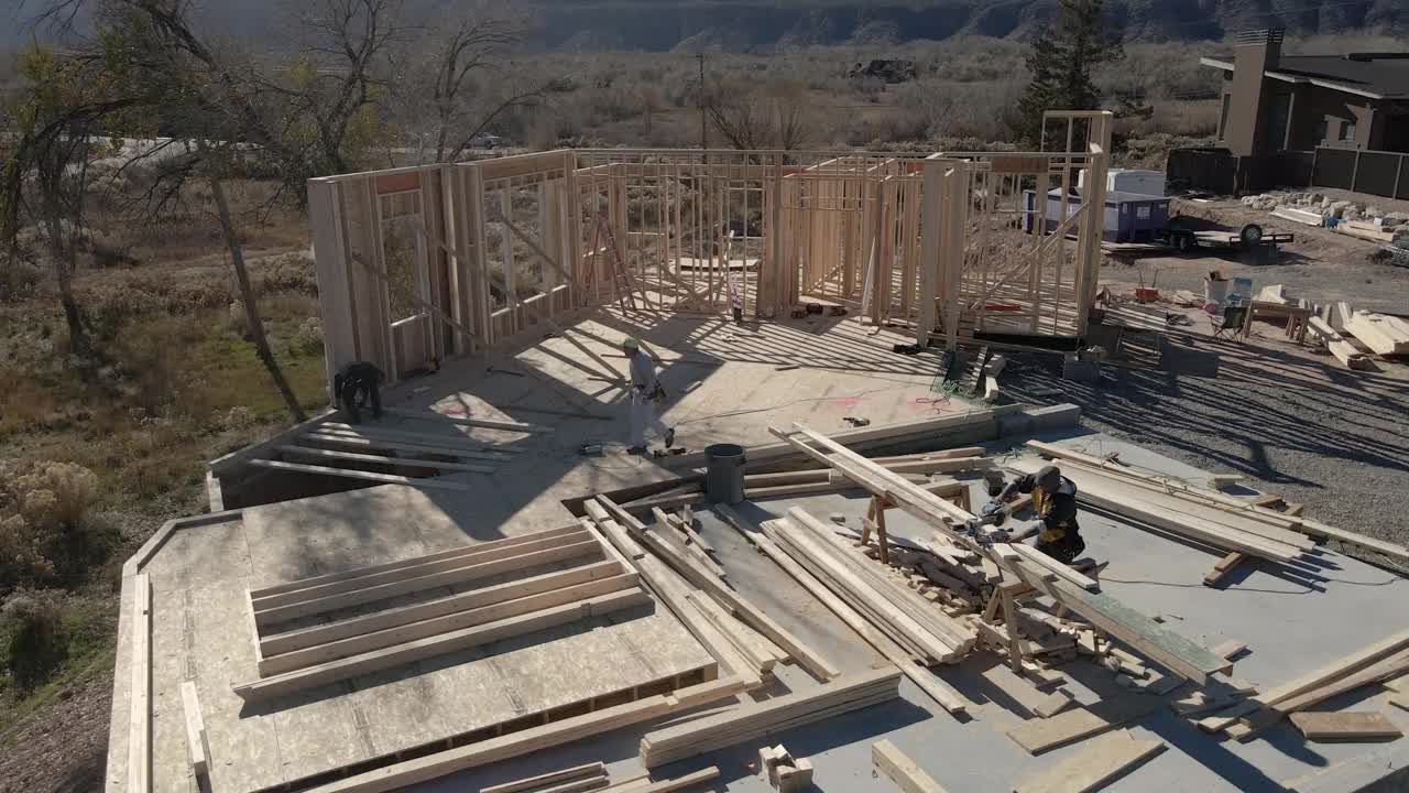 无人机住宅建筑工地与三个高加索框架木匠工作的墙壁视频素材