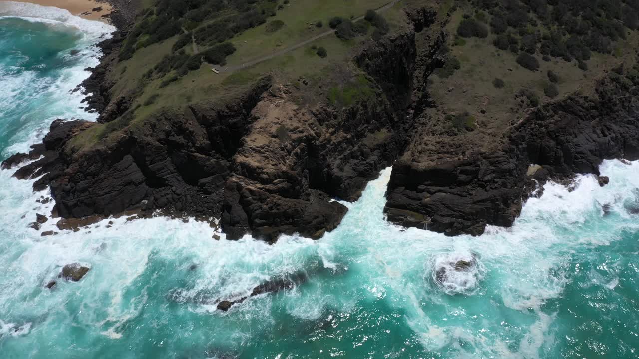 在澳大利亚新南威尔士州帽子岬岬，海浪撞击悬崖底部的鸟瞰图。视频素材