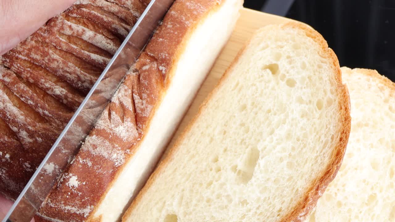 特写的女人切新鲜的面包在砧板上。切面包做三明治视频下载