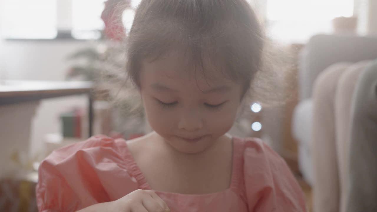 亚洲可爱的小女孩吃巧克力，微笑着看着镜头。视频素材
