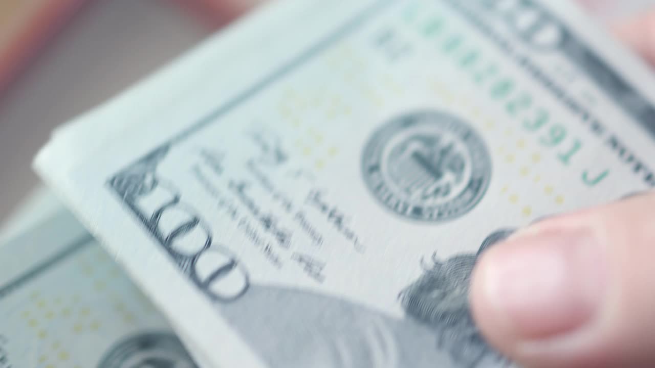 一个女人的手在细数100美元钞票的特写视频素材