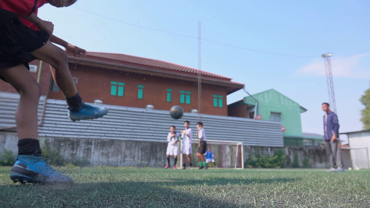 男孩足球运动员向球门踢球的慢动作视频下载