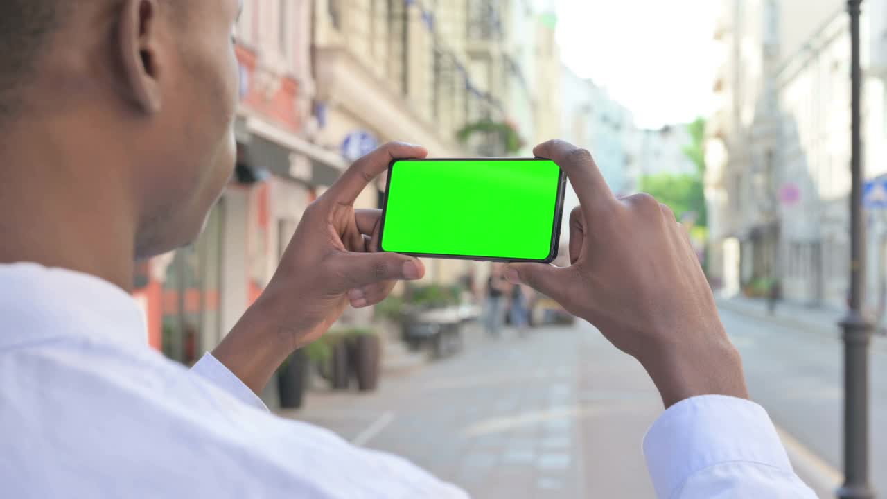 户外非洲人看着绿色屏幕的智能手机视频素材
