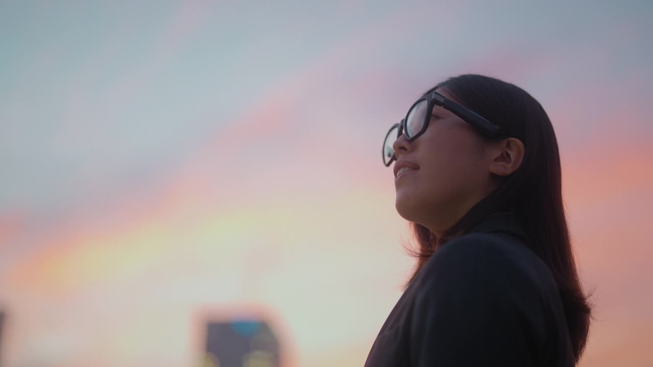 年轻的女商人带着智能眼镜在市中心拍摄日落照片视频下载