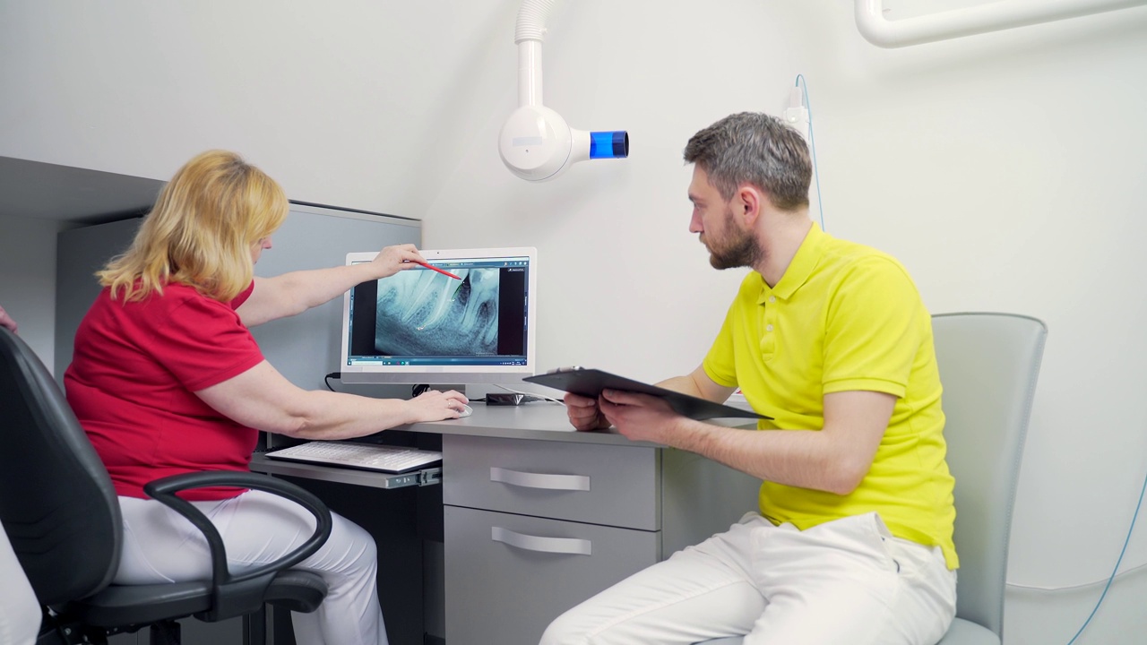 牙科医生小组在牙科诊所讨论和检查x光图像。看着电脑视频素材