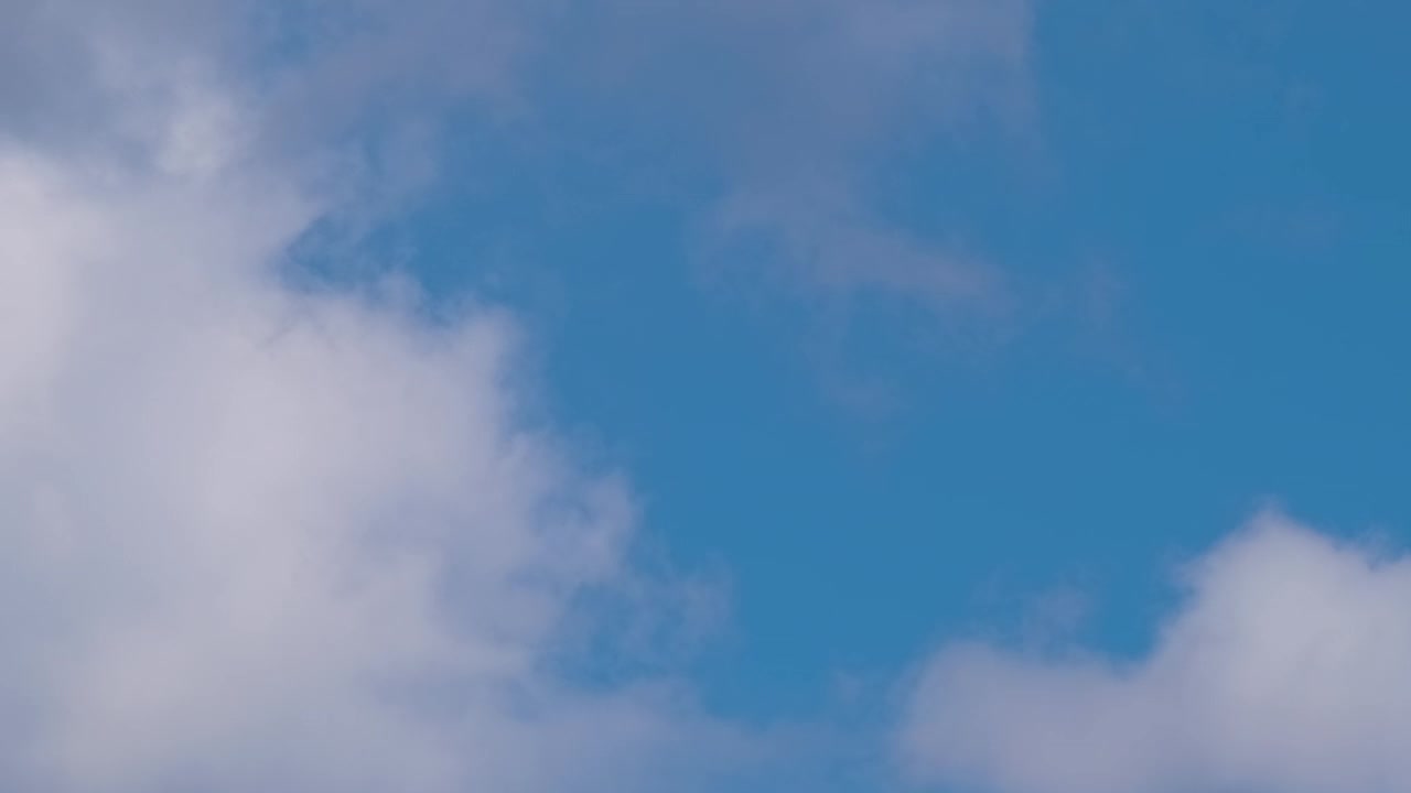 远处的喷气式客机在蓝天上的高空飞行，白云留下烟雾的痕迹。空中旅行的概念视频素材