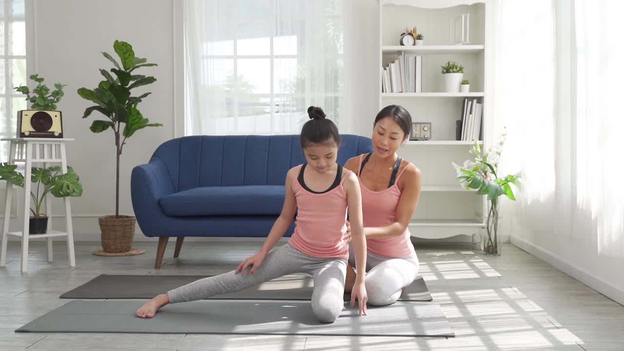一位妇女在家里教她的孩子瑜伽视频素材