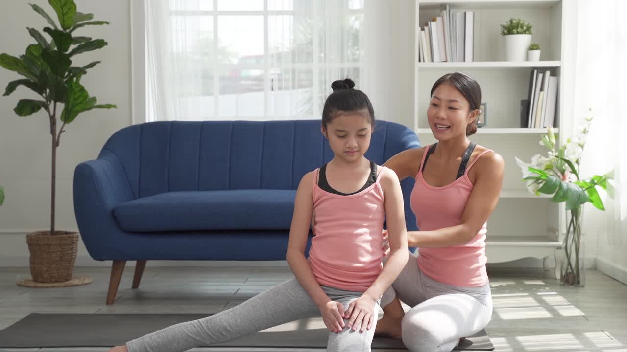 一位妇女在家里教她的孩子瑜伽视频素材