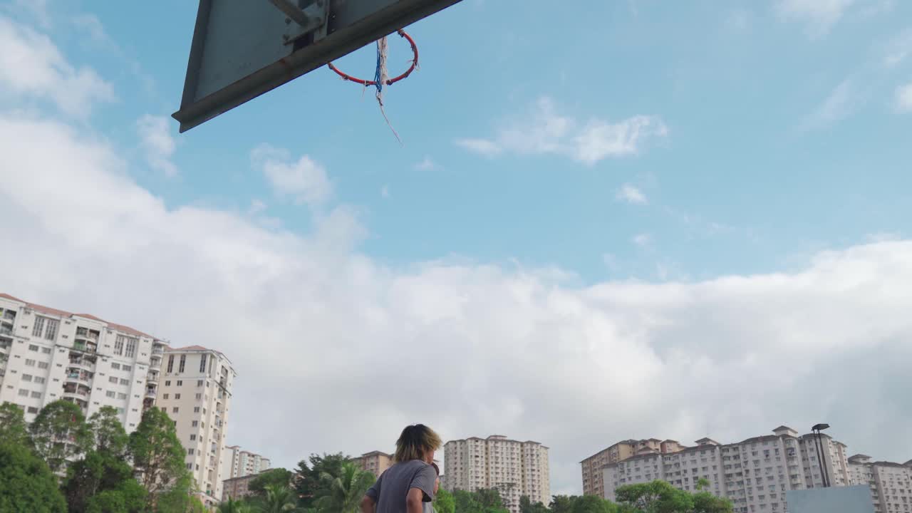 Z一代亚洲中国少年男孩挑战球员，并在周末早上和朋友们一起练习篮球视频下载