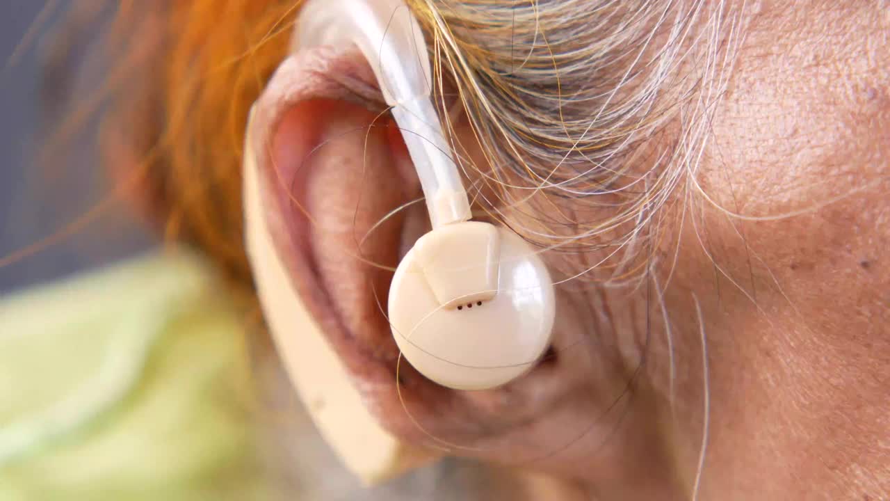 助听器概念，一位有听力问题的高级女性。视频素材
