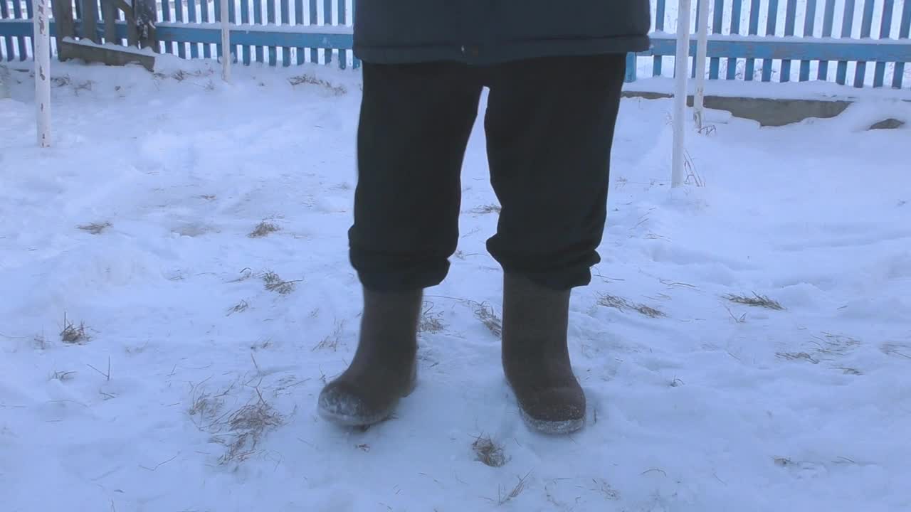 一个穿着冬衣和毡靴的男人走在街上视频素材