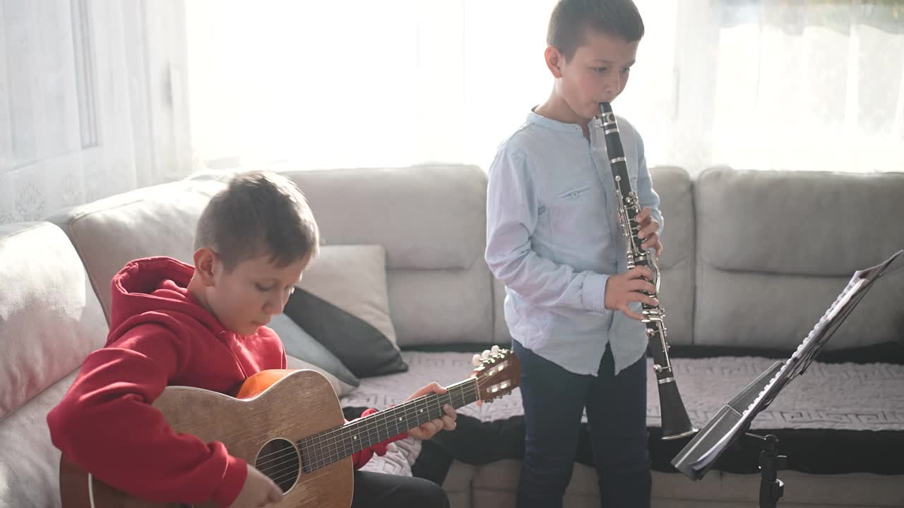两个男孩兄弟姐妹用吉他和单簧管一起练习音乐视频下载