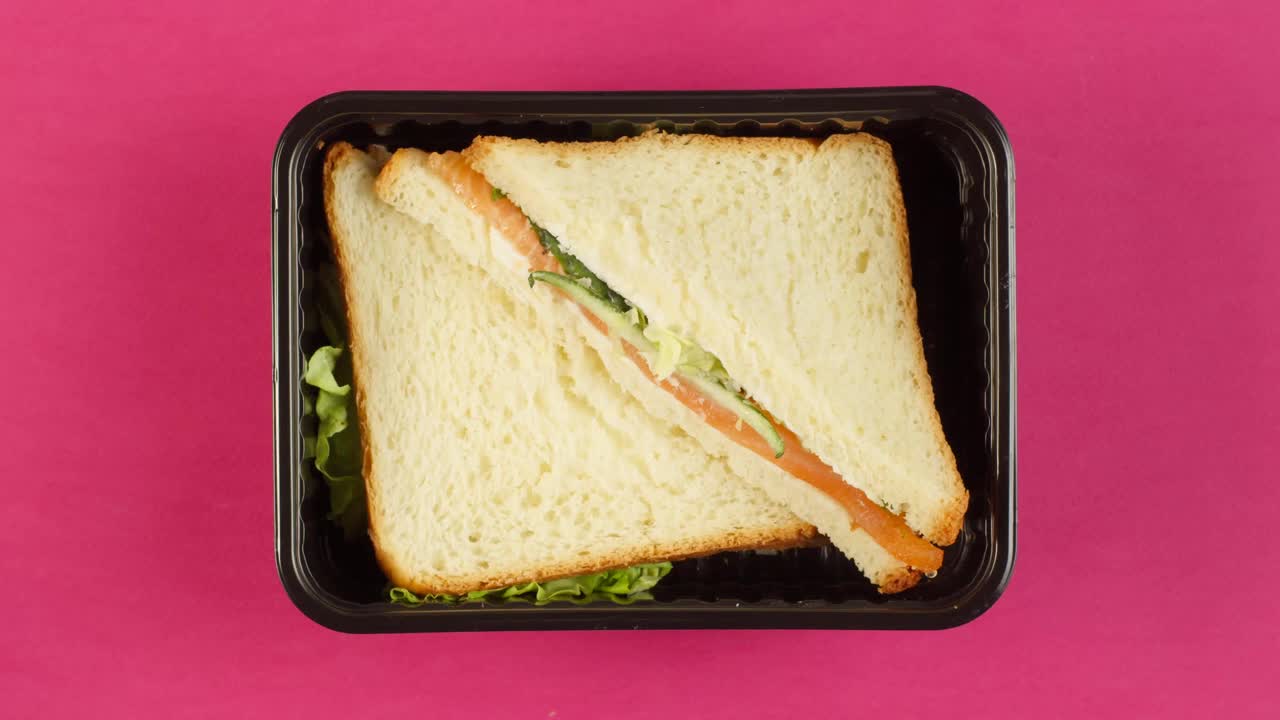 鲑鱼三明治特写。食物递送顶视图，带走餐在一次性容器。午餐盒配素菜，面包配鱼及生菜。健康的饮食习惯。餐饮服务理念视频下载