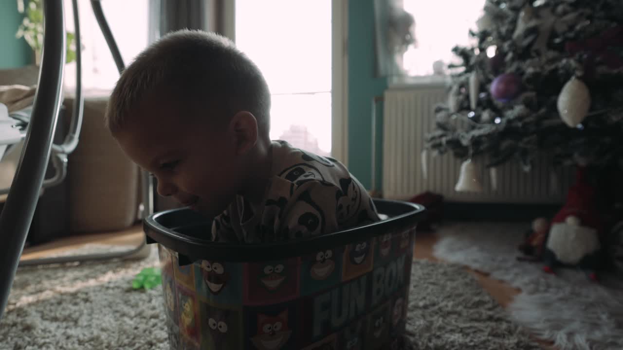 可爱的白人小男孩坐在客厅的玩具盒里，享受着美好的一天。快乐童年，童年观念。游戏时间，在家玩的概念。圣诞节的时候视频下载