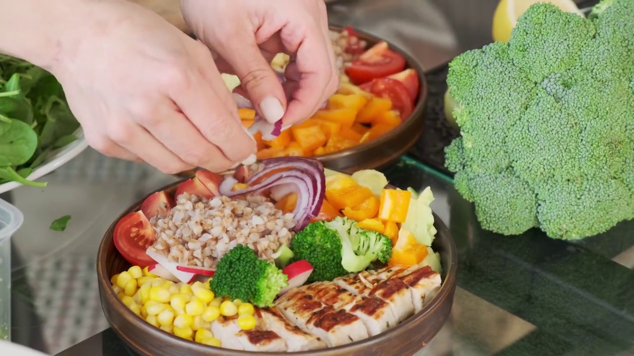 素食沙拉的制作过程近距离-厨师的手把切碎的洋葱和蔬菜放在碗里视频下载