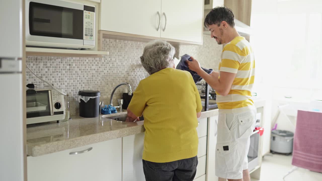 一个男人和他的老妈妈在她的厨房里一起洗碗视频素材