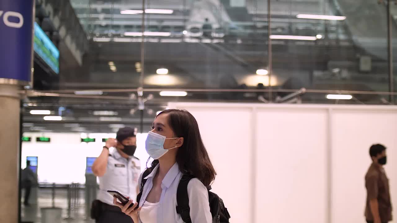 亚洲妇女寻找登机口从机场的到达和起飞板视频素材