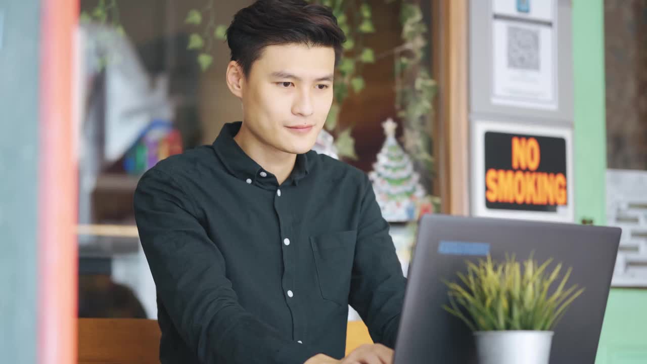 微笑的专业年轻亚洲中国商人工作使用笔记本电脑在露天咖啡馆视频下载