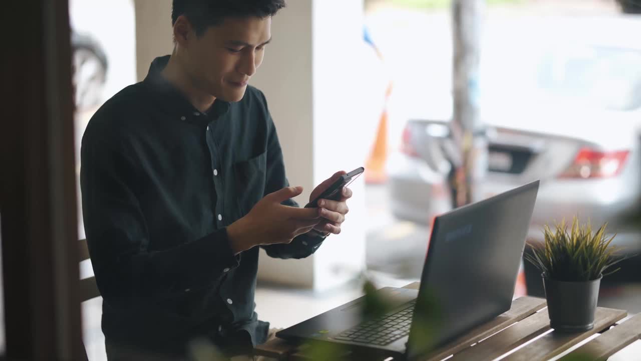 微笑的专业年轻亚洲华人商人在露天咖啡馆用笔记本电脑工作视频下载