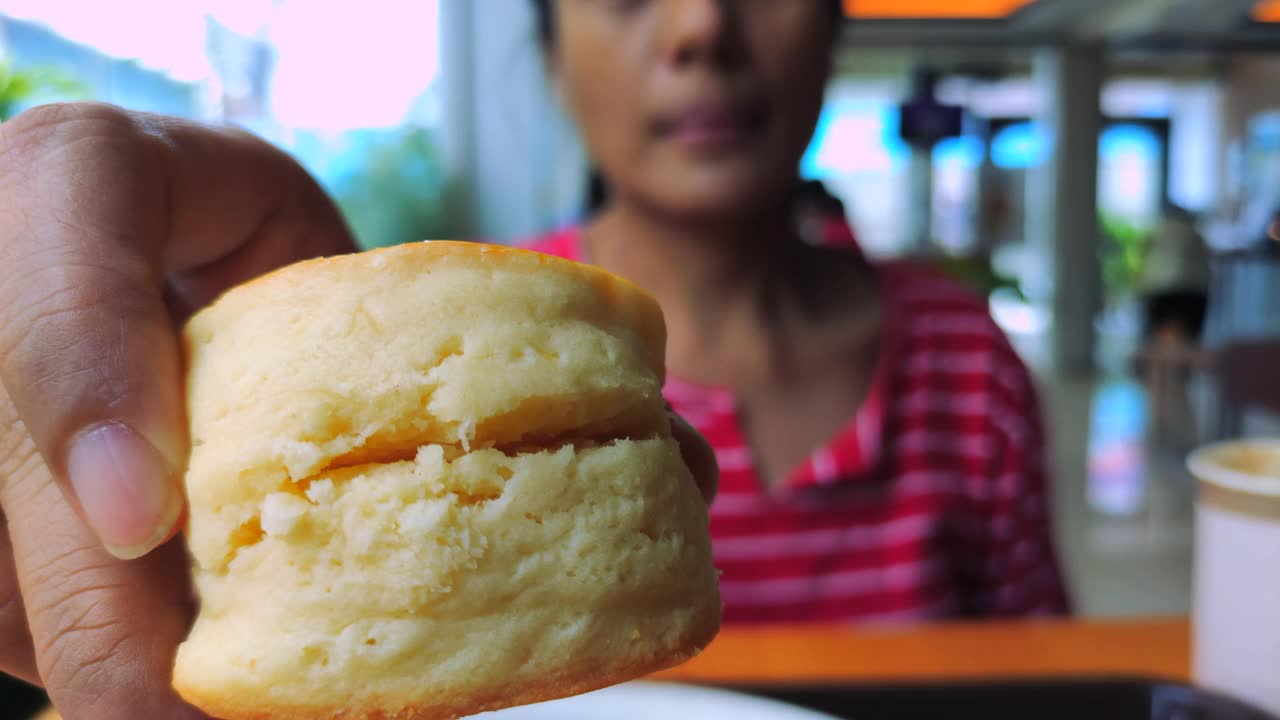 一个女人在咖啡馆咬烤饼，慢动作视频素材