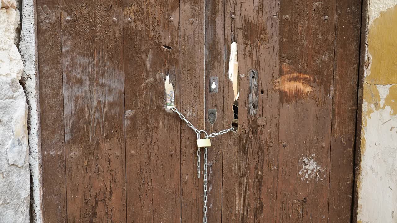 一座废弃的老房子的门用铁链和挂锁锁着。视频下载