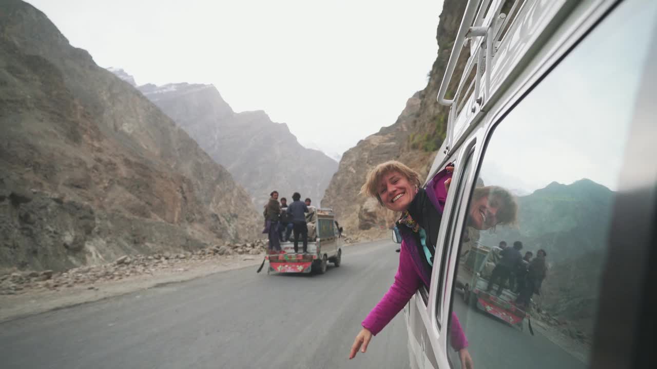 一位女士从货车的窗户望着巴基斯坦北部的山脉，竖起大拇指视频素材