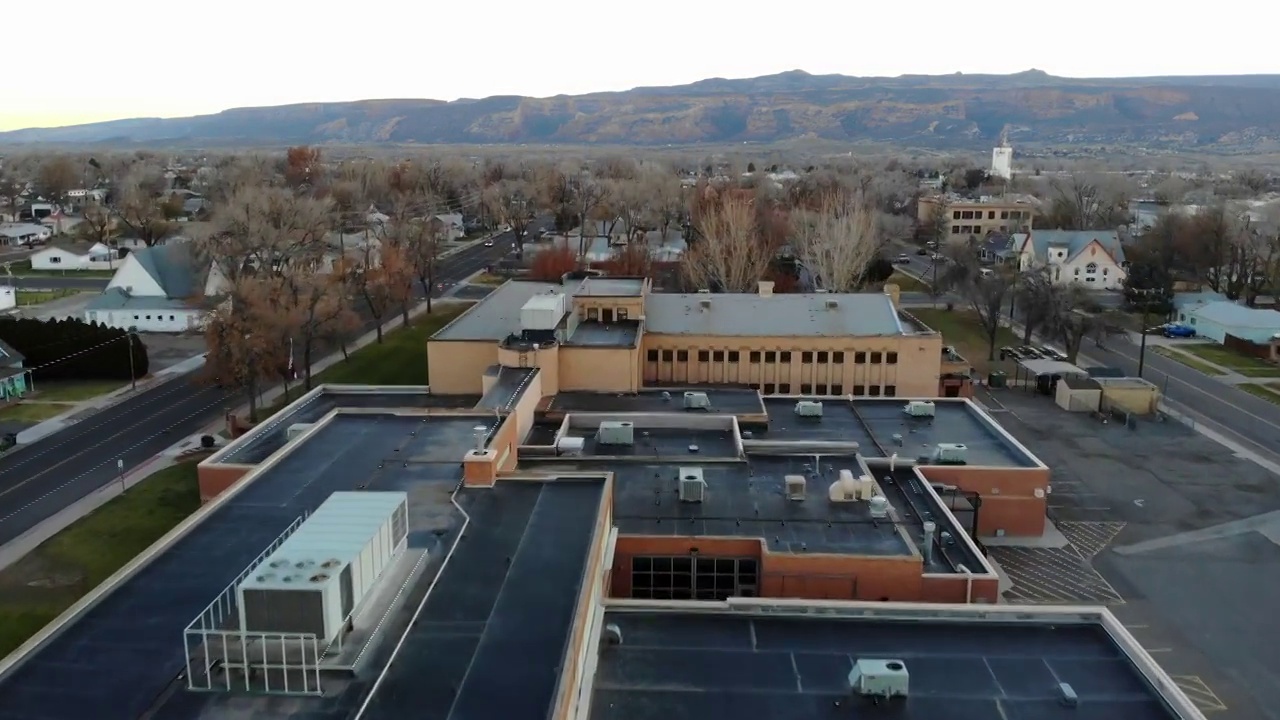 大型学校建筑的无人机镜头设置在一个小镇的中心，背景是美丽的山脉视频素材