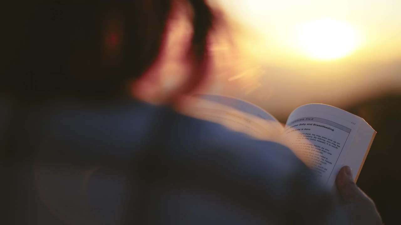 女人在户外放松，在夕阳下阅读一本书视频素材