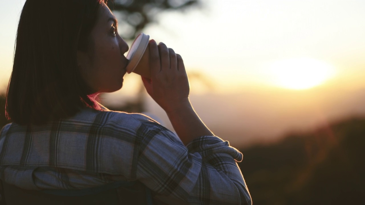 女人在户外放松与咖啡杯在山上的日落时间视频素材